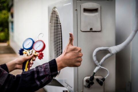 A man giving thumbs up to an air conditioner while Choosing the Right HVAC Contractor.