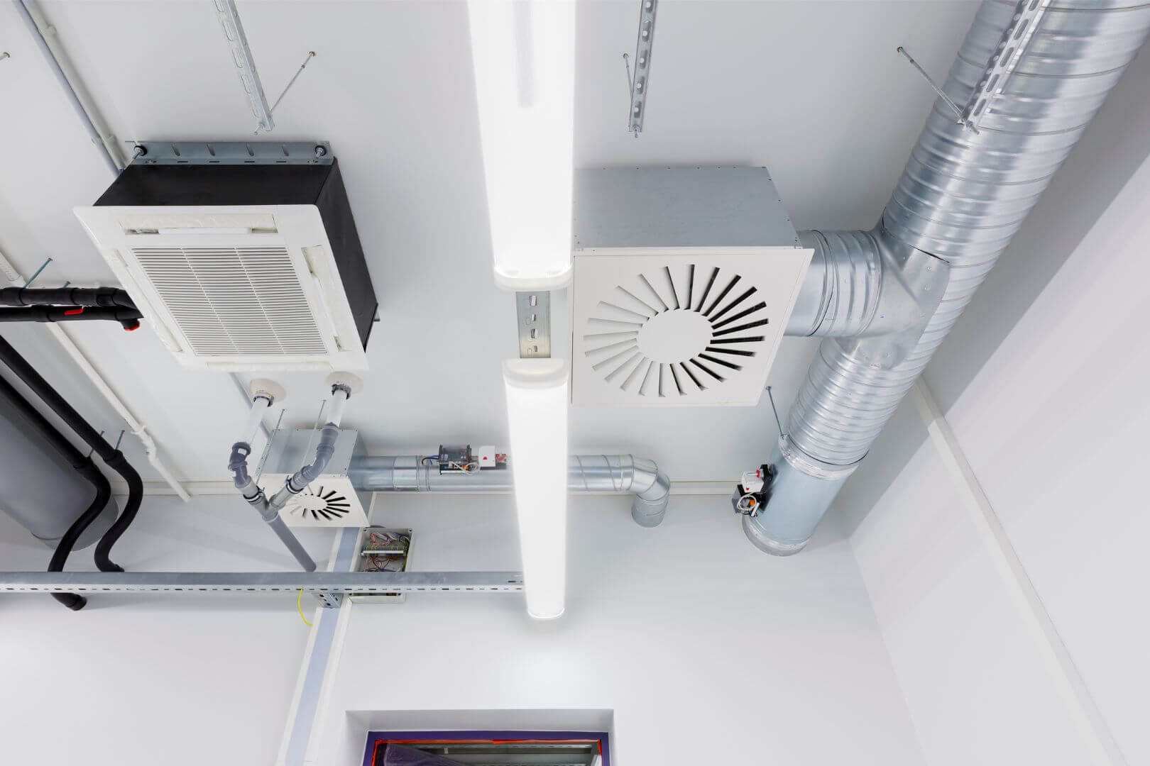 A commercial room with multiple air conditioning units and ducts for HVAC services.