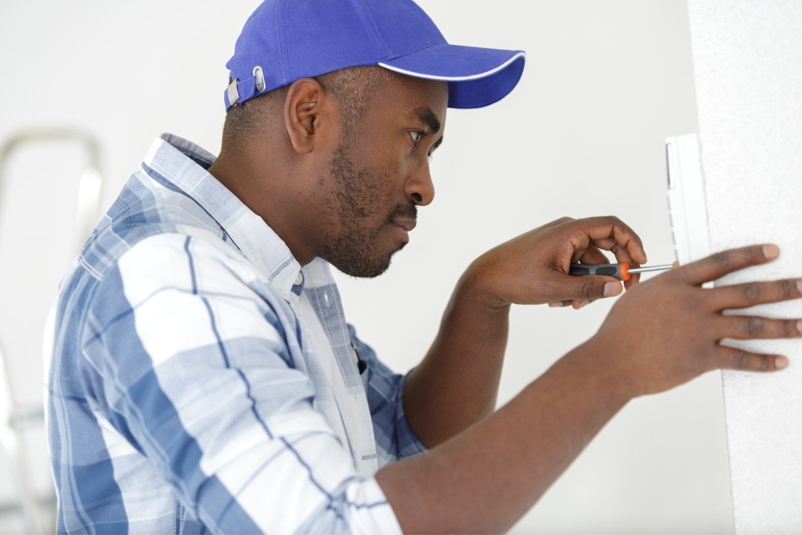 A man is providing services by working on a light switch.