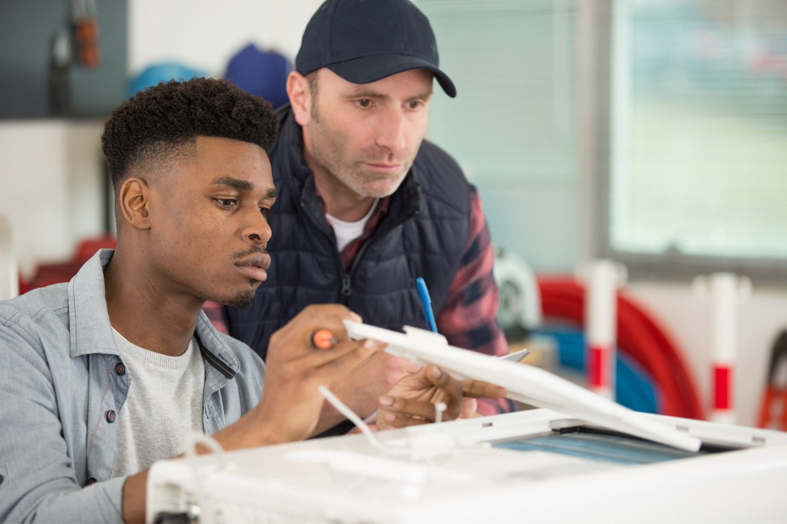 A man and a young man working on an air conditioning machine.