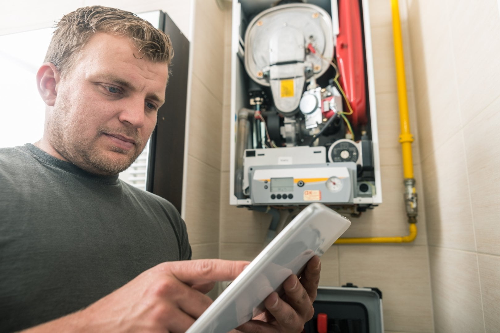 A man using a tablet in front of a heating appliance.