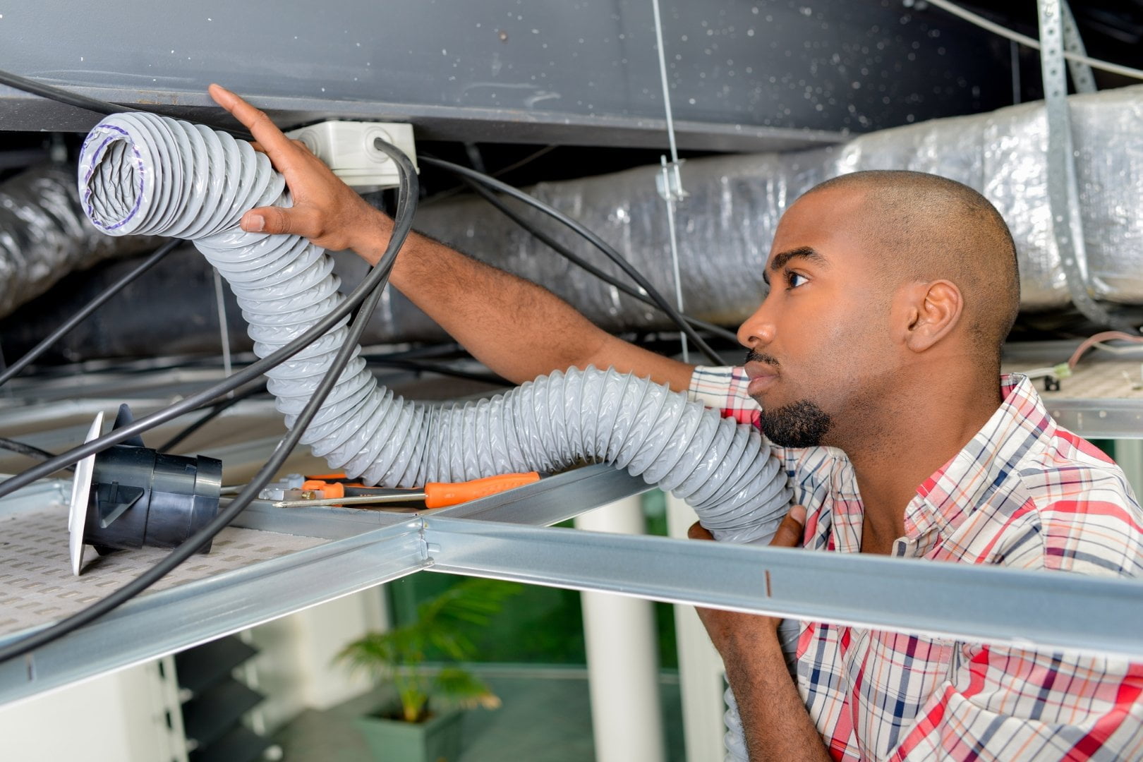 A man utilizing commercial HVAC services to clean a duct using a hose.