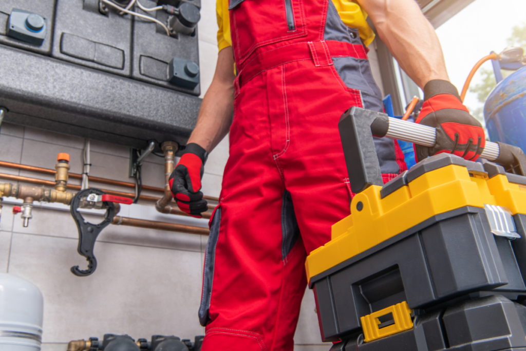 A plumber in overalls holding a toolbox specializing in Winter HVAC Maintenance.