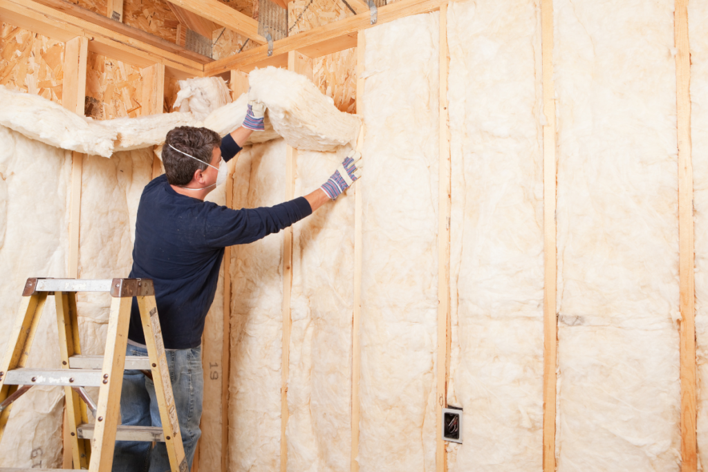A man performing winter HVAC maintenance by installing insulation in a home.