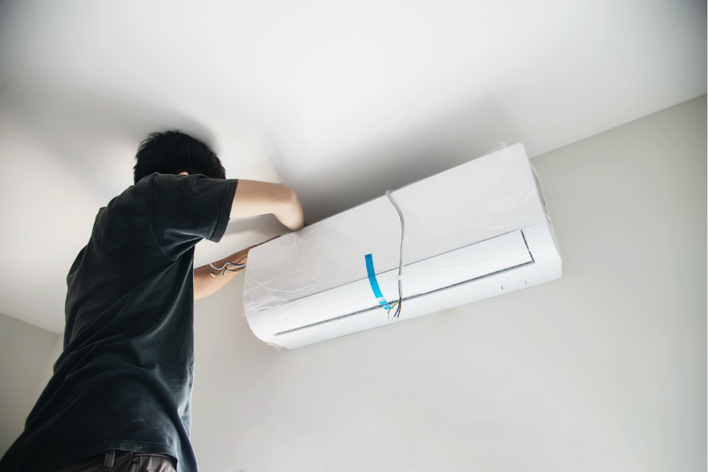 A man installing an energy-efficient air conditioner in a room.