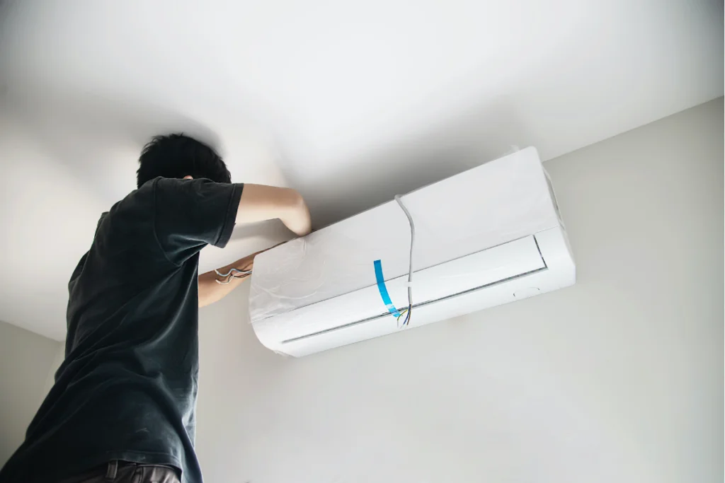 A man installing an energy-efficient air conditioner in a room.