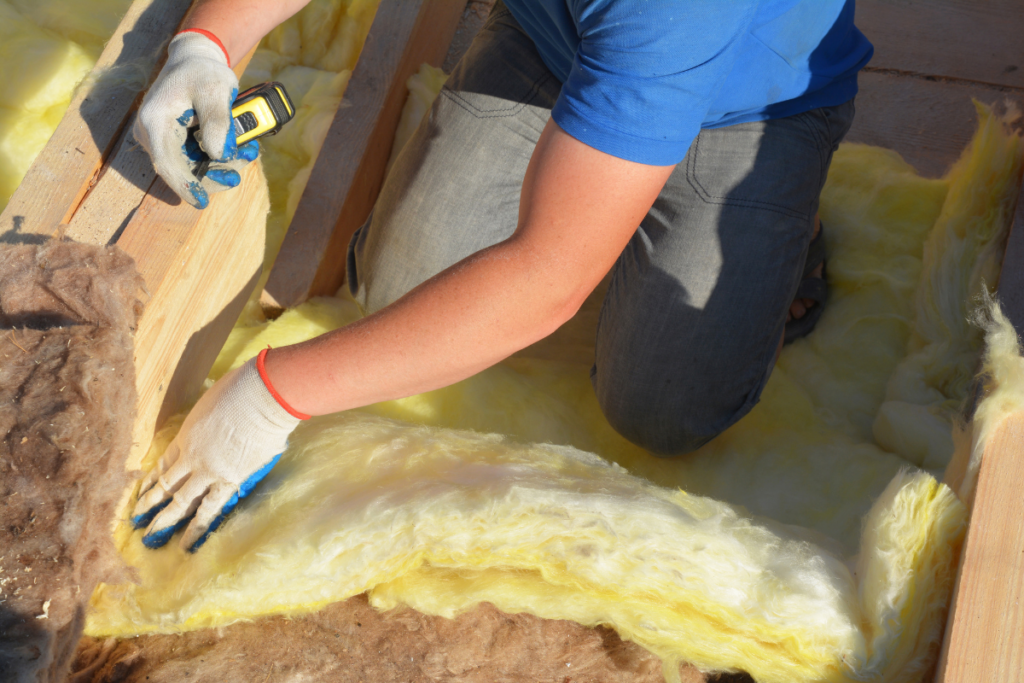 A man implementing energy efficiency measures while working with insulation on a roof.