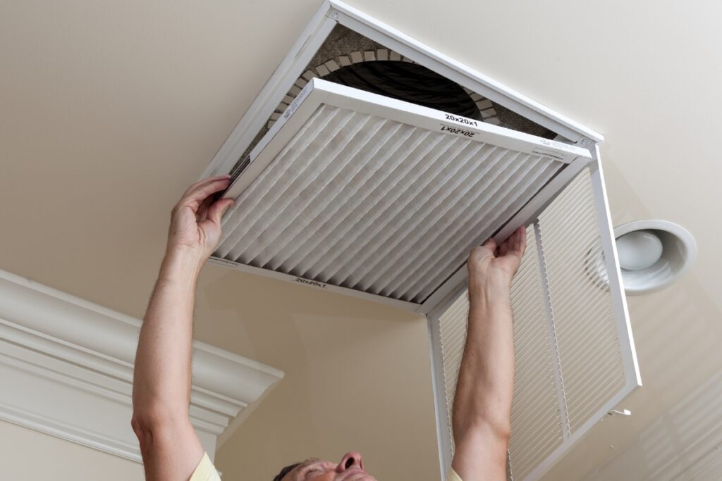 A man holding up an HVAC vent.