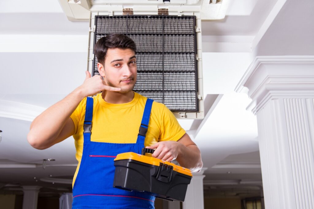 A man in blue overalls, specialized in HVAC, holding a toolbox.