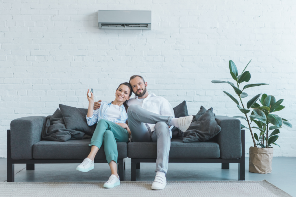 A man and woman sitting on a couch with a smart air conditioner.