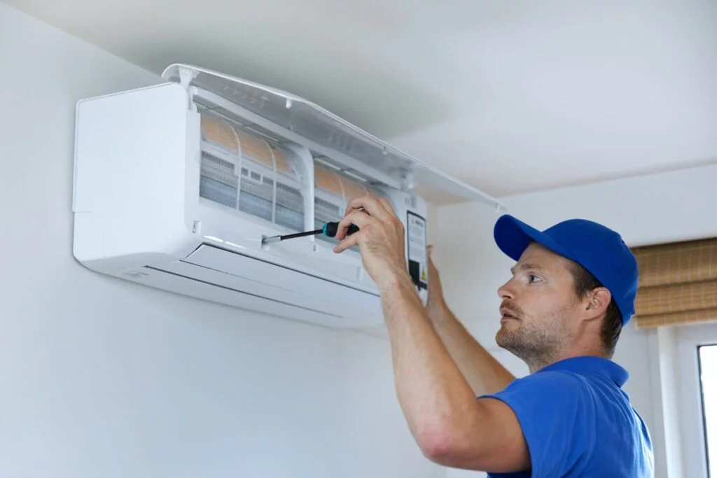 A technician servicing an air conditioning unit indoors for optimal Georgia climate control.