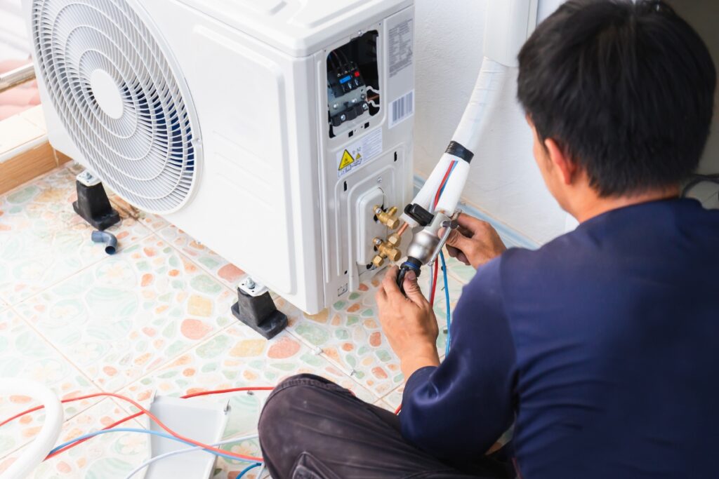 A technician repairing common HVAC issues in an air conditioning unit, using tools while focused on the equipment.