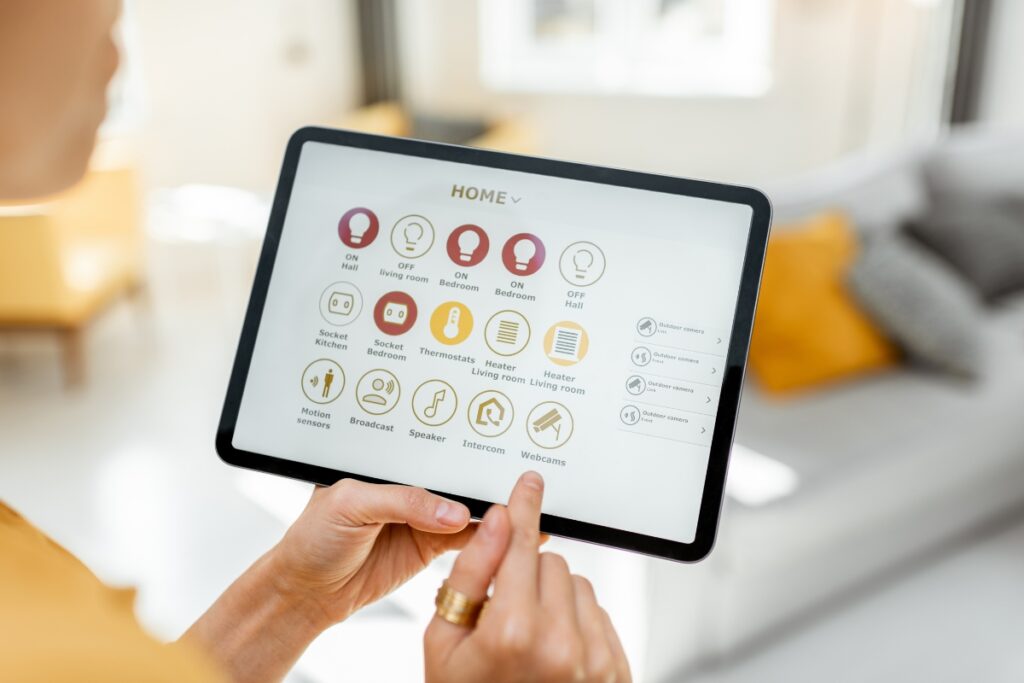 A person operates a smart home control panel on a tablet, effortlessly managing various functions such as lights, thermostat, and HVAC system from a screen displaying multiple icons.