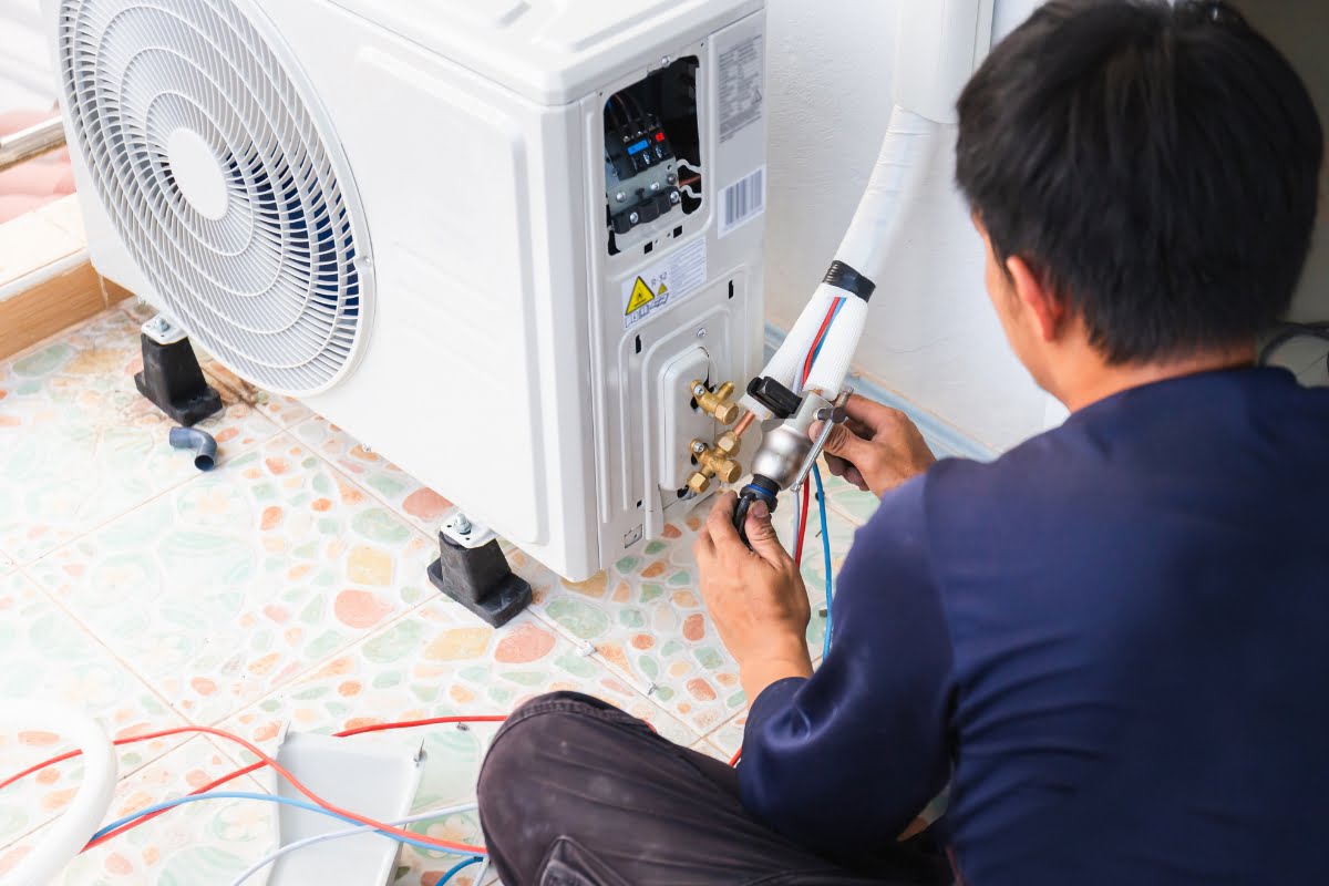 A technician installs or repairs an HVAC unit, working with various wires and tools on a tiled floor to ensure a healthy home environment.