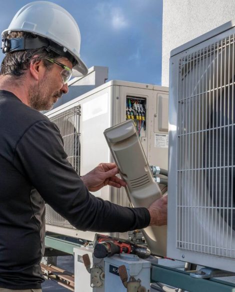 A man providing commercial HVAC services by working on an air conditioning unit.