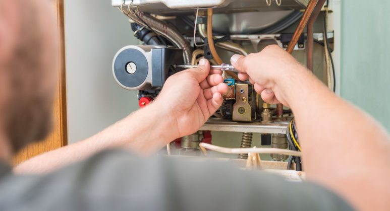 A man is servicing a hot water heater.