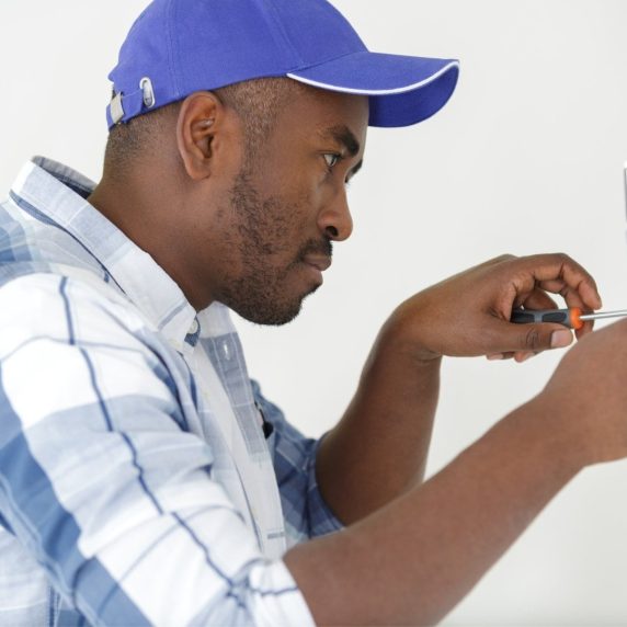 A man is providing services by working on a light switch.