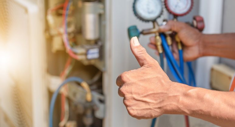 A man giving a thumbs up to an air conditioning unit.