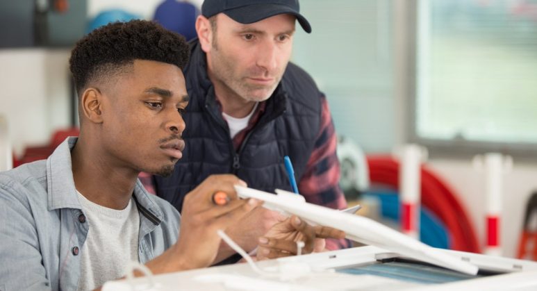 A man and a young man working on an air conditioning machine.