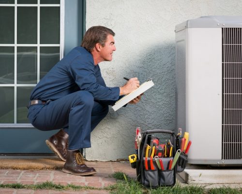 A man fixing an air conditioner outside a home.