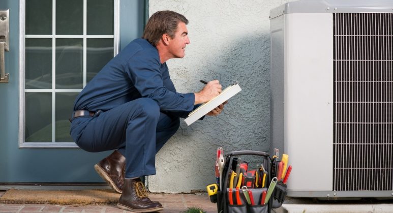 A man fixing an air conditioner outside a home.