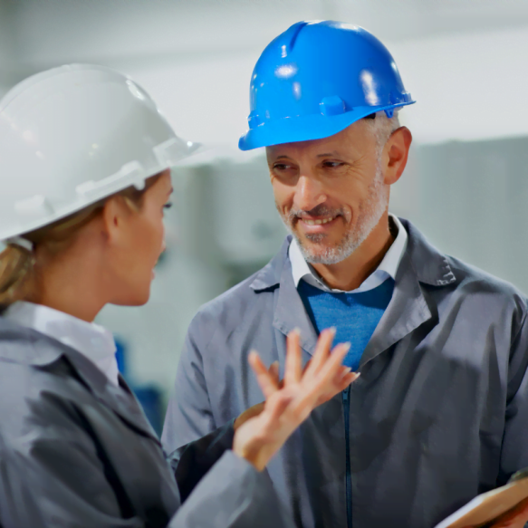 Two workers in hard hats conversing in a factory for the Atlanta HVAC Company.