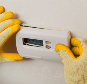 A person is holding a thermostat for an Atlanta HVAC company.