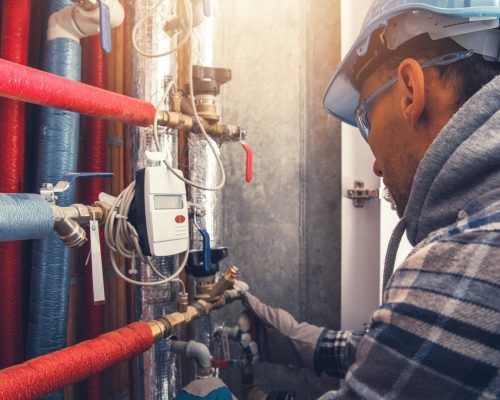 A plumber is servicing a hot water pipe for commercial HVAC systems.