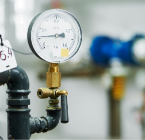 A pressure gauge on a pipe in a factory monitored by a Dallas HVAC Company.