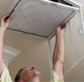 A Decatur HVAC technician holds up an air conditioner in a room.