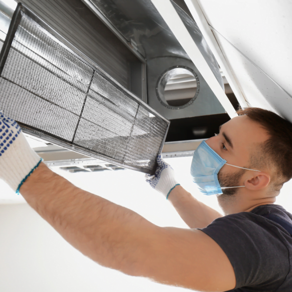 A man employed by the Decatur HVAC Company is working on an air conditioner, donning a mask and gloves.