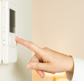 A representative from a Duluth HVAC Company demonstrating a thermostat in a room.