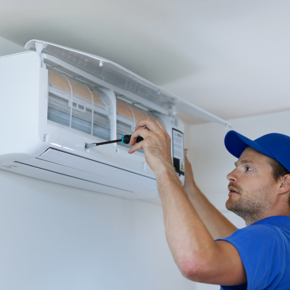 A man from Duluth HVAC Company fixing an air conditioner in a room.