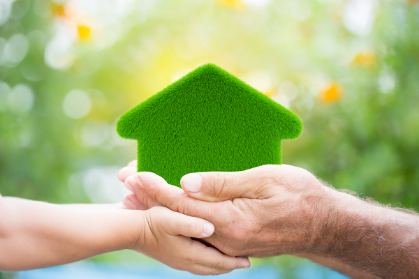 A man and a child holding an eco-friendly HVAC-equipped green house in their hands.