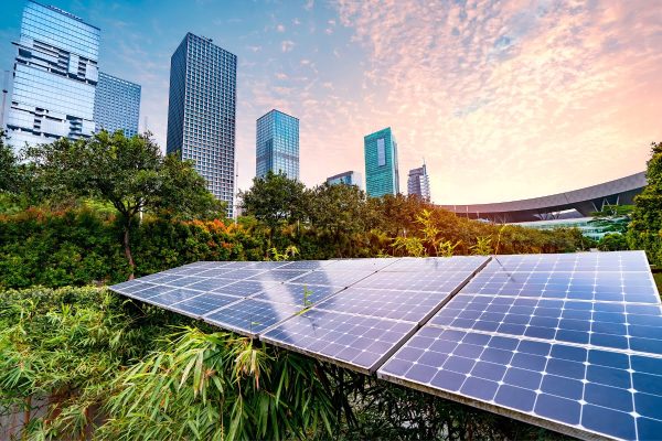 Solar panels on a rooftop in front of a city skyline combine renewable energy and the benefits of energy-saving tips for businesses.