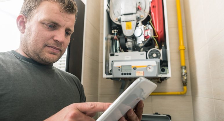 A man using a tablet in front of a heating appliance.