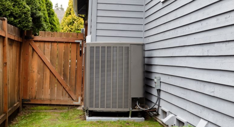 An air conditioning unit REQUIRING maintenance services in the backyard of a house.