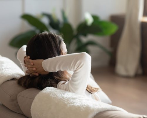 A woman is sitting on a couch feeling stressed and frustrated.