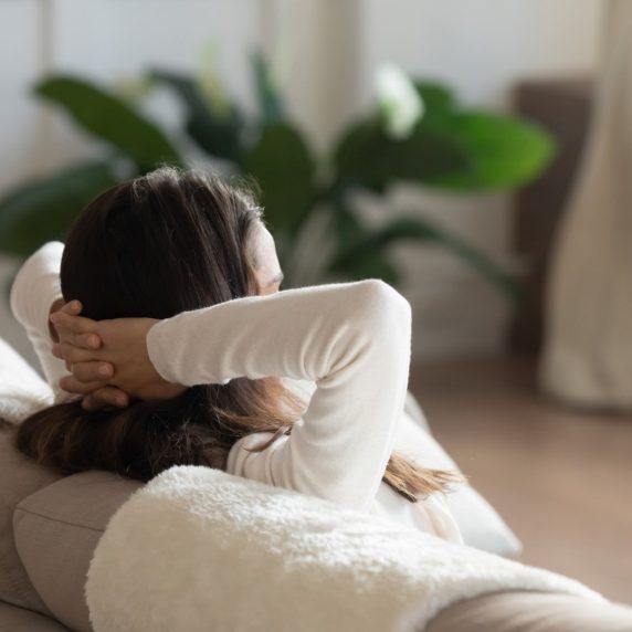 A woman is sitting on a couch feeling stressed and frustrated.