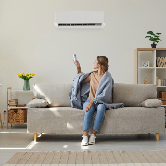 A woman sitting on a couch in a living room with an HVAC system.