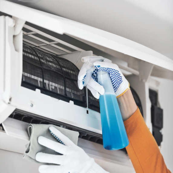 A Johns Creek HVAC technician cleaning an air conditioner.