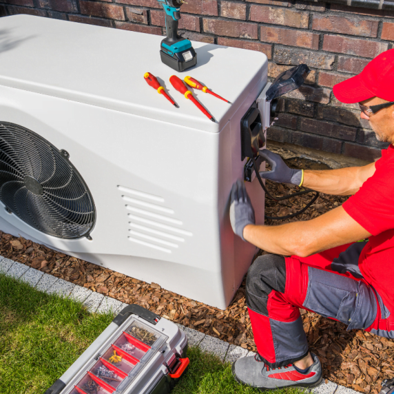 A man fixing an air conditioner in front of a house for Kennesaw HVAC Company.