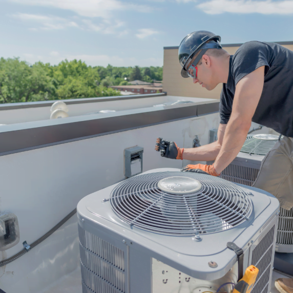 A technician from Smyrna HVAC Company repairing an air conditioner on a roof.